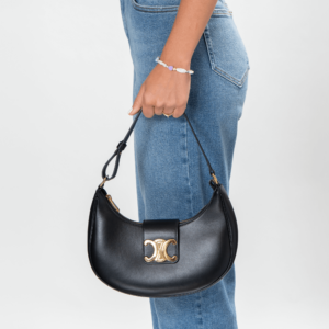 Frau trägt eine schwarze Leder-Schultertasche mit goldener Hardware der Marke Celine.