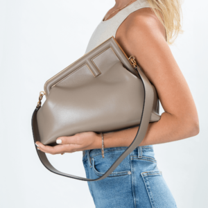 Frau trägt eine beige Clutch-Tasche mit goldener Hardware der Marke Fendi.