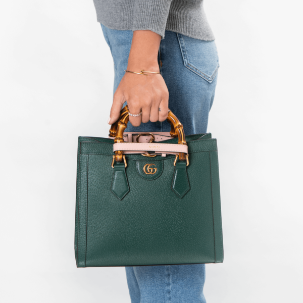 Frau trägt dunkelgrüne Handtasche aus Leder mit Bambusgriffen der Marke Gucci.